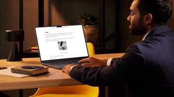 Business professional reading an email on a laptop containing a QR code link, representing a potential phishing attempt via PDF attachment.